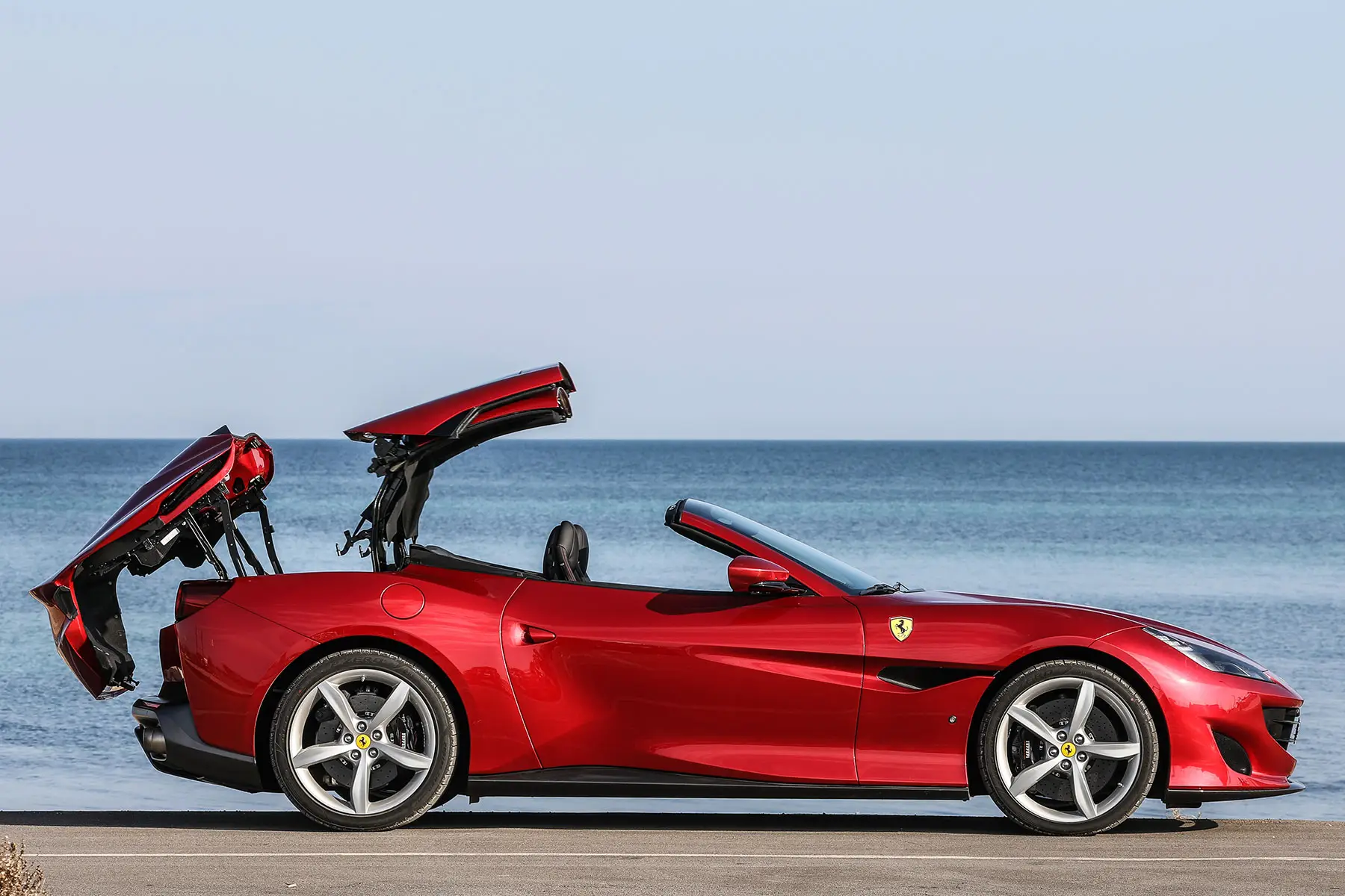2018 Ferrari Portofino convertible side profile in Rosso Corsa with retractable hardtop open
