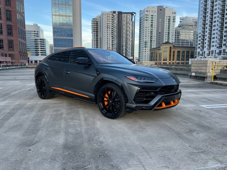 Grey 2019 Lamborghini Urus parked in an urban setting with city skyline
