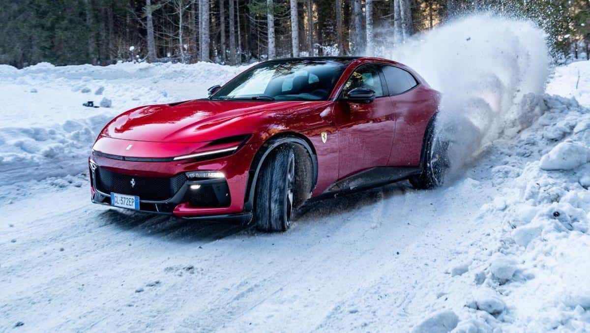 2023 Ferrari Purosangue V12 cornering through snow with rear wheel spray showing all-wheel drive capability